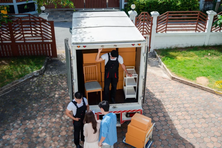 A couple checking boxes as movers unload a truck